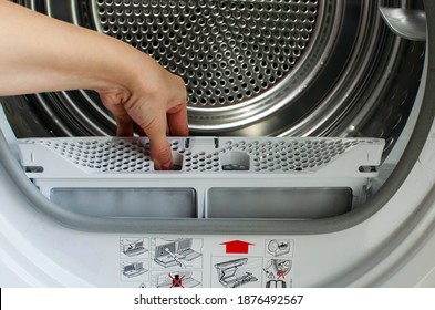 A housewife holds a lint trap from a front-loading tumble dryer. Woman's hand