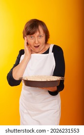 Housewife With Homemade Cakes On A Colored Background.
Shot Of Joyful Positive Mature Woman Enjoying Birthday Party Eating Apple Pie. Senior Woman Posing With Dessert. Celebration, Food And Dessert.