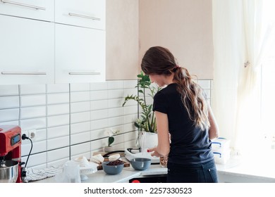 housewife in the kitchen pours food into a bowl - Shutterstock ID 2257330523