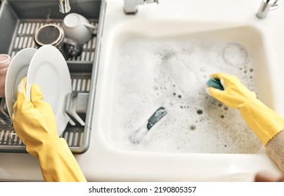 Housewife, maid or cleaner hands washing dishes in the kitchen sink for home hygiene, wearing rubber gloves. Contact us for cleaning solutions or professional domestic household chores service. - Shutterstock ID 2190805357