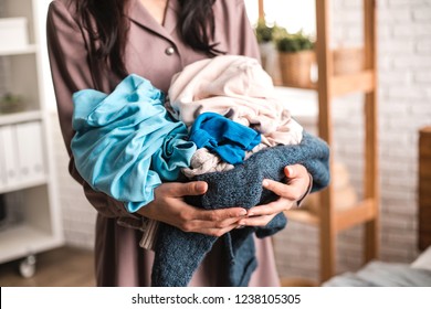 Housewife Neatly Holds A Pile Of Clothes Near The Bed. Concept Of Housekeeping.