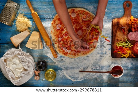 Housewife preparing a pizza for your family, arranges all the ingredients in the order, onions, tomatoes, peppers, sausage falls asleep all the cheese on top