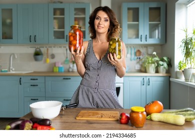 Housewife Preserves Vegetables At Home. Made At Home Canned Vegetables. Beautiful Brunette Woman In The Kitchen At Home Preserves Vegetables In Glass Jars.