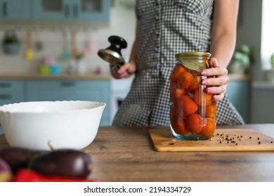 Housewife Preserves Vegetables At Home. Made At Home Canned Vegetables. Beautiful Brunette Woman In The Kitchen At Home Preserves Vegetables In Glass Jars.