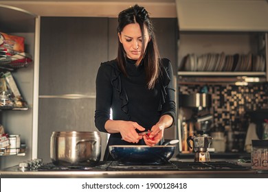 Housewife Slicing Tomatoes In The Cooking Pan. Young Italian Woman Making Pasta Sauce In The Kitchen.