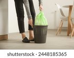 Housewife throwing away garbage, taking of plastic garbage bag from the trash bin in the apartment	