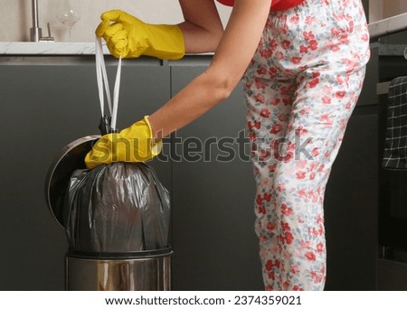 Housewife throwing away garbage, taking of plastic garbage bag from the trash bin in the apartment