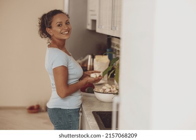 A housewife washes mushrooms in the sink in the kitchen turning her head to the camera and smiling - Powered by Shutterstock