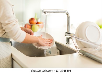 Housewife washing dishes in the kitchen sink
