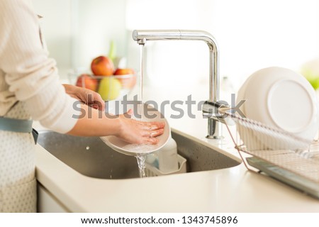Housewife washing dishes in the kitchen sink