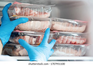 Housewife Wearing Blue Latex Gloves Stocking Fresh Pork In Refrigerator Freezer. People Panic And Prepare To Pandemic Quarantine.  Stay At Home Policy From Government During Coronavirus Or COVID-19