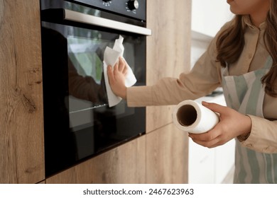 Housewife wiping oven with paper towel in kitchen, closeup - Powered by Shutterstock