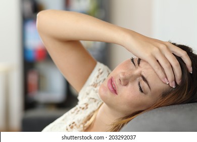 Housewife woman in a couch with headache and a hand on forehead - Powered by Shutterstock