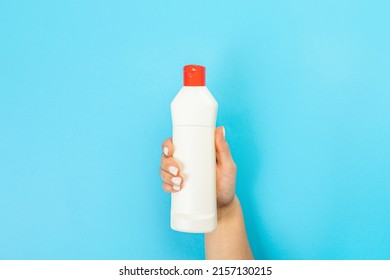 Housewife's hand holds a spray with cleaning agent on a blue background. Detergent for various surfaces in the kitchen, bathroom and other rooms. Close-up. Light pastel blue background.