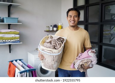 Housework. asian Man doing laundry at home loading clothes into washing machine