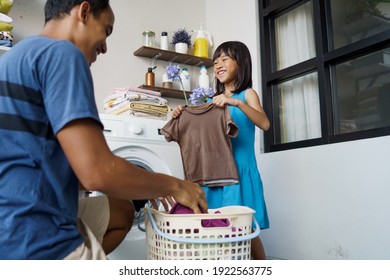 Housework. Asian Man Doing Laundry At Home Loading Clothes Into Washing Machine