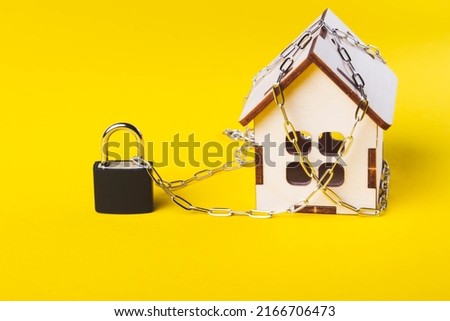 Housing arrest. Castle house. Small toy house and a chain with a lock. Eviction for non-payment. The locked door to the house.