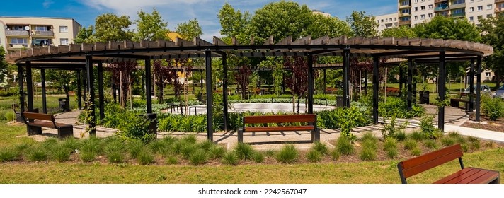Housing estate mini park. Visible decorative pergola. Green recreational areas, walking alleys, beautiful bushes and flowers, benches etc.   - Shutterstock ID 2242567047