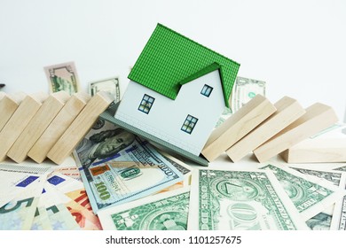 Housing Market Going To Crash Concept With Miniature Plastic House Fall With Domino Pieces On Cash Banknotes
