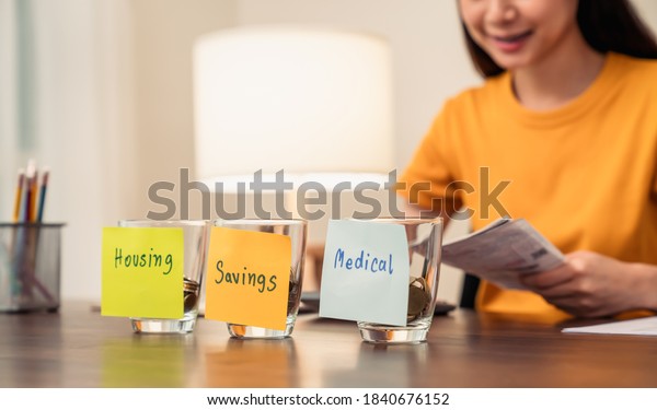 housing, medical with\
saving notepaper pasted on the bottle with coins inside, young\
woman uses a calculator and plan income and expenditures divided by\
categories.