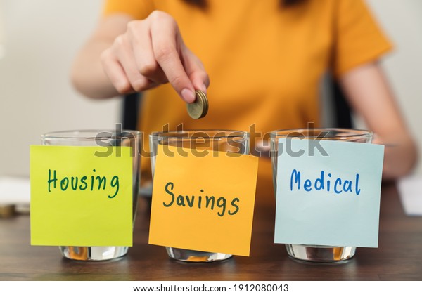 housing, medical with
saving notepaper pasted on the bottle with coins inside, young
woman uses a calculator and plan income and expenditures divided by
categories.