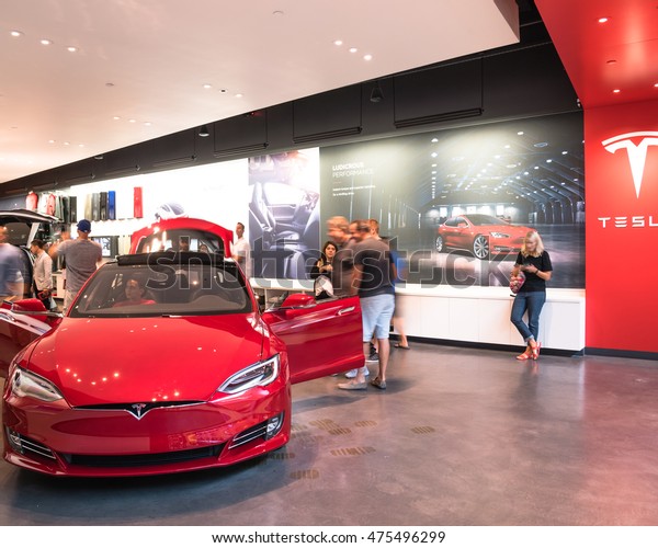 HOUSTON, TEXAS - AUG 27, 2016: Inside Tesla showroom\
with Model S 2016 red in Galleria, guests engage with company\
staff. It is an American public company designs, manufactures, and\
sells electric car