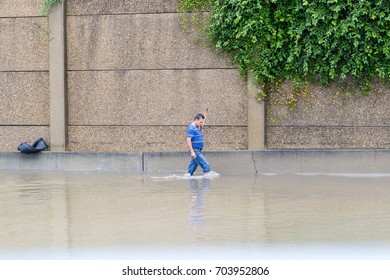 Houston, Texas - August 27, 2017: Houston resident walk across the flooded street in Houston, Texas, USA. Heavy rains from hurricane Harvey caused many flooded areas in Houston.