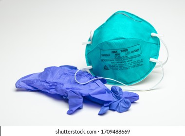 Houston, TX - April 20, 2020: An Unused Turquoise 3M N95 Protective Respirator Face Mask Next To A Blue Pair Of Rubber Gloves.