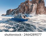 Hovercraft parked on a blue cracked ice of the lake Baikal. Tourists transportation and entertainment on winter Baikal.