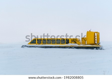 Hovercraft in winter tundra. Air cushion on the beach. Yellow hover craft under snow.