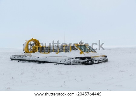 Hovercraft in winter tundra. Air cushion on the beach. Yellow hover craft under snow.
