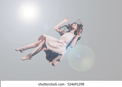 Hovering beauty. Studio shot of attractive young woman hovering in air