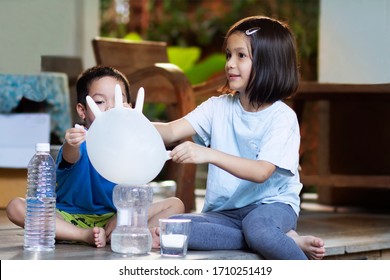 How baking Soda and Vinegar inflates rubble glove balloons  experiment. Asian preschool kids  learn to make an acid-base reaction. The reaction  carbon dioxide gas that bubbles up and glove bigger.