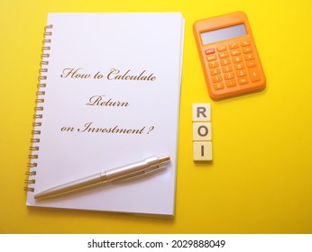 How To Calculate Return On Investment? Note Book, Calculator, Pen And Square Alphabets 