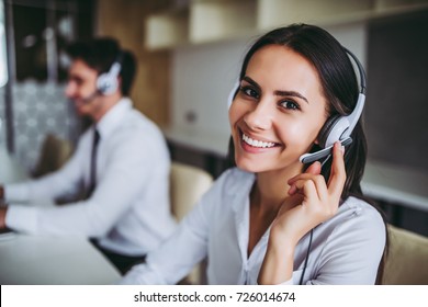 How can I help you? Beautiful call center workers in headphones are working at modern office. - Shutterstock ID 726014674