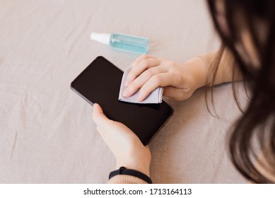 How To Clean, Sanitize Your Phone In Home. Cleaning Mobile Phone To Eliminate Germs, Coronavirus Covid-19. Man Hands Cleaning Smartphone By Disinfectant Spray.