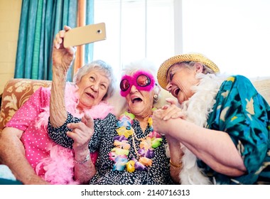 How Does This Thing Work. Shot Of A Group Carefree Elderly People Wearing Funky Costumes And Getting Close For A Selfie Inside Of A Building.