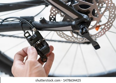 how to maintenance a mtb hydraulic disc brake caliper : Repairman holding a Hydraulic rear disc brake caliper on a mountain bike.