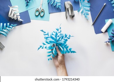 How To Make Paper Beautiful Christmas Toy Snowflake To Decorate Room With Children At Home. Step By Step Instructions. Top View. Hands Making DIY Winter Craft Project. Step 11. Enjoy Ready Toy