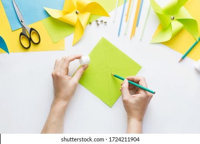 How To Make Paper Green Windmill Toy With Children At Home. Step By Step Instructions. Hands Making DIY Summer Project. Step 4. In The Middle Of Sheet Draw Circle Using Round Object, E.g Glue Caps