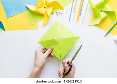 How To Make Paper Green Windmill Toy With Children At Home. Step By Step Instructions. Hands Making DIY Summer Project. Step 5. Cut Sheet In Lines To Circle In Center, Getting Half-cut Triangles