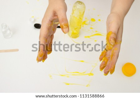 how to make slime. A female hands holds yellow homemade slime is a children's toy close up. Composition sodium tetraborate and glue. Top view.
