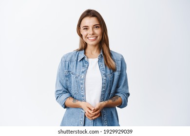 How may I help you. Smiling young woman with fair hair holding hands together and looking friendly at camera, happy emotions, white background