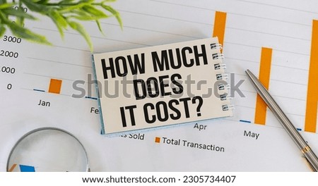 How Much Does it Cost text on a card against the background of a blank notebook on a desk, a business concept