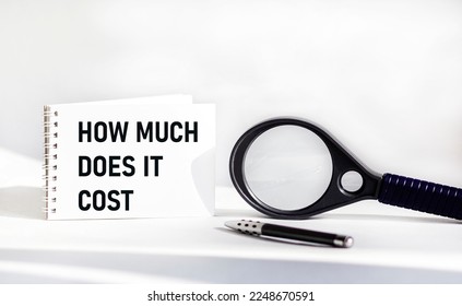How much does it cost, write on a notepad on a white background, next to a magnifying glass with a pen