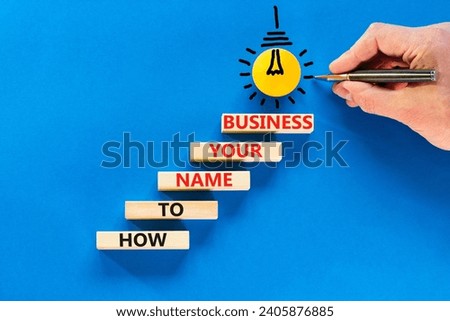 How to name your business symbol. Concept words How to name your business on wooden blocks. Beautiful blue table blue background. Businessman hand. How to name your business concept. Copy space.