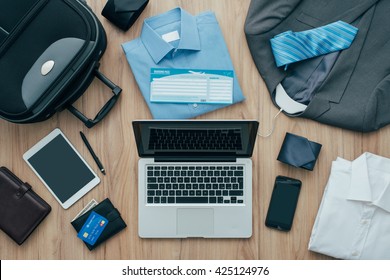 How to pack for a business trip: all items that needs to be packed, a bag and a laptop on a desktop, travel concept