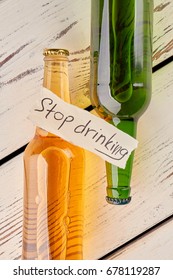 How to stop drinking. Full bottles of alcohol, paper message, old wooden boards.