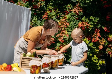 How to Store and Preserve Vegetables for long Time. Canning and Preserve Vegetables From Garden. Happy family mother and kid canning vegetables in the garden in summer day