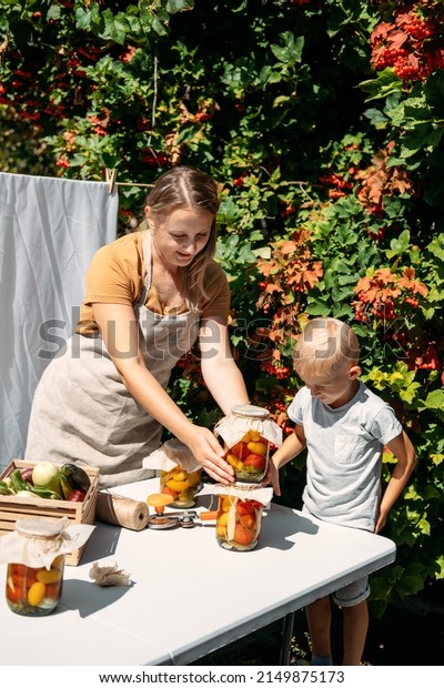 How to\
Store and Preserve Vegetables for long Time. Canning and Preserve\
Vegetables From Garden. Happy family mother and kid canning\
vegetables in the garden in summer\
day